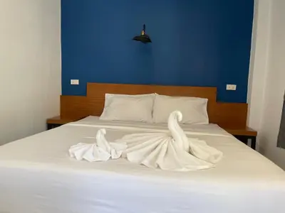 a bed with white towels on it with a blue wall at PP. Valentine Bungalow in Phi Phi Don
