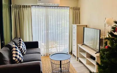 a living room with a couch and a christmas tree at Nai Yang Beach Holiday Rental Apartement - Title Residence in Nai Yang Beach