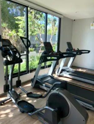 a gym with three tread machines in front of a window at Nai Yang Beach Holiday Rental Apartement - Title Residence in Nai Yang Beach