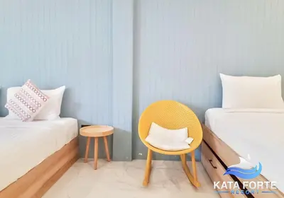 a room with two beds and a chair and a table at Kata Forte Resort in Kata Beach