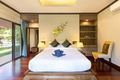 a bedroom with a large white bed and a chair at Villa Carlos, Luxury 7 BDR Private Pool Villa, Baan Bua Nai Harn, Phuket in Rawai Beach