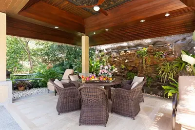 a patio with a table and chairs and a stone wall at Villa Carlos, Luxury 7 BDR Private Pool Villa, Baan Bua Nai Harn, Phuket in Rawai Beach