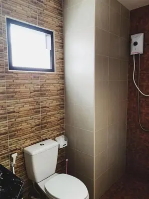 a bathroom with a toilet and a television on the wall at Himma's Apartment in Kamala Beach