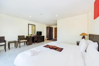 a bedroom with a large white bed and a desk at My Hotel Phuket in Patong Beach
