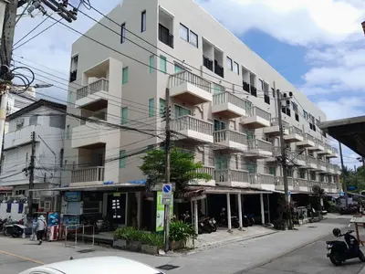 a white building with balconies on a city street at My Hotel Phuket in Patong Beach