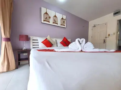 a bedroom with a large white bed with towels on it at Sea Boss Homestay in Kata Beach