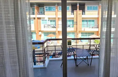 a balcony with a table and chairs and a building at Sea Boss Homestay in Kata Beach