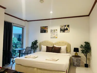 a bedroom with a large bed and a table at Cocoon Omaya Guest House in Patong Beach