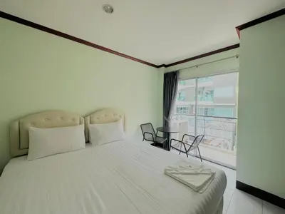 a bedroom with a large white bed with a window at Cocoon Omaya Guest House in Patong Beach