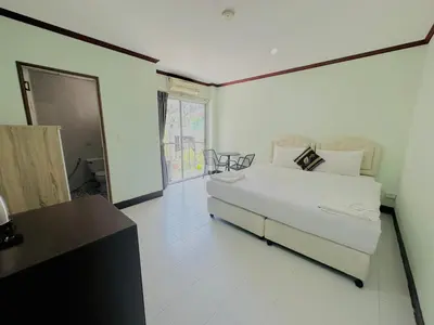 a bedroom with a bed and a table and a window at Cocoon Omaya Guest House in Patong Beach