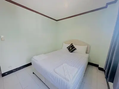 a small white bed in a room with blue curtains at Cocoon Omaya Guest House in Patong Beach
