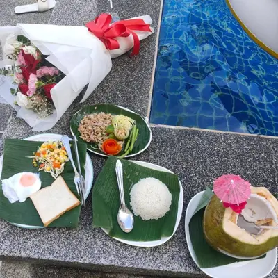 a table with plates of food next to a pool at Pailin Hill Hotel in Patong Beach