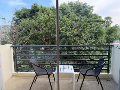 two chairs and a table on a balcony with trees at Casa De Coral Boutique Hotel in Kata Beach