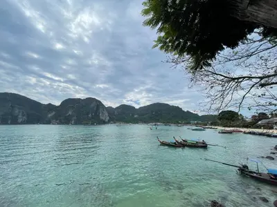 two boats on a body of water with mountains in the background at Bodega Koh Phi Phi in Phi Phi Don