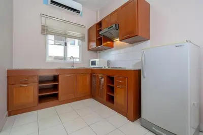 a kitchen with wooden cabinets and a refrigerator at Jungceylon Villa - quiet location, pool, maid in Patong Beach
