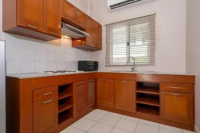 a kitchen with wooden cabinets and a sink at Jungceylon Villa - quiet location, pool, maid in Patong Beach