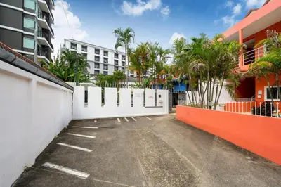 a parking lot with a white fence and palm trees at Jungceylon Villa - quiet location, pool, maid in Patong Beach