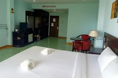 a bedroom with a white bed and a living room at Riviera Patong in Patong Beach