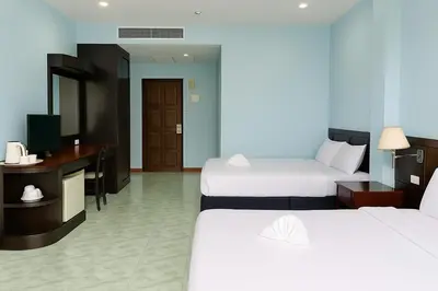 a hotel room with two beds and a desk at Riviera Patong in Patong Beach