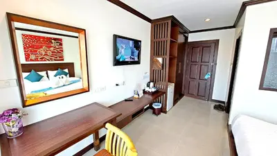 a room with a desk and a bed and a mirror at Southern Comfort Patong in Patong Beach