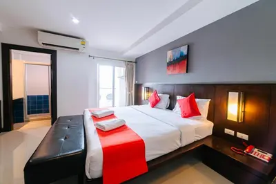 a bedroom with a large white bed with red pillows at Ratana Hotel Sakdidet, PHUKET TOWN in Phuket Town