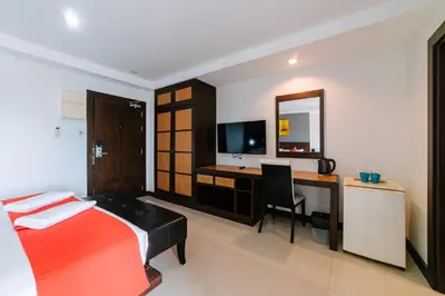 a bedroom with a bed and a desk and a television at Ratana Hotel Sakdidet, PHUKET TOWN in Phuket Town
