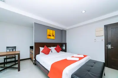 a bedroom with a bed with red pillows and a desk at Ratana Hotel Sakdidet, PHUKET TOWN in Phuket Town