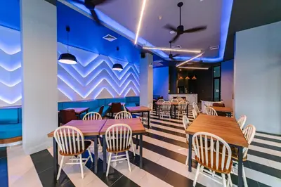 a restaurant with wooden tables and chairs and a blue wall at Ratana Hotel Sakdidet, PHUKET TOWN in Phuket Town