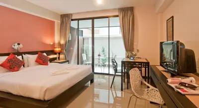 a bedroom with a bed and a desk with a tv at Ratana Residence Thalang in Thalang