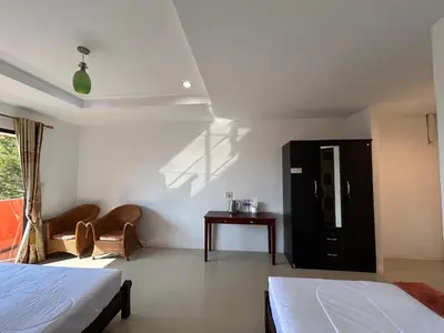 a bedroom with two beds and a table and a window at Relaxation guesthouse in Thalang