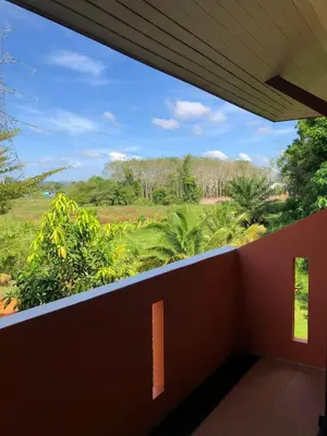 a balcony with a view of a field and trees at Relaxation guesthouse in Thalang