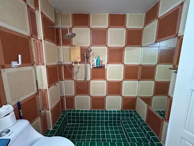 a bathroom with a shower with a green tile floor at Relaxation guesthouse in Thalang