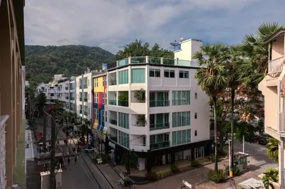 a white building with palm trees in a city at Grand Orlov Apart Hotel in Patong Beach