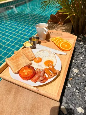 a plate of breakfast food on a tray next to a pool at WoLin Lemon Resort in Ban Saiyuan (1)