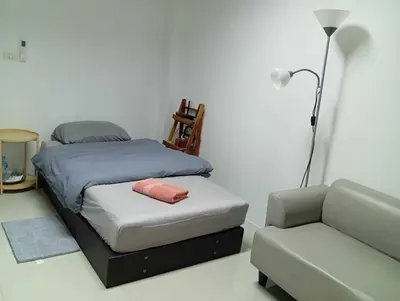 a bedroom with a bed and a chair and a lamp at Baan7984 Rawai in Rawai Beach