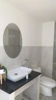 a bathroom with a sink and a toilet and a mirror at RadHut in Chalong