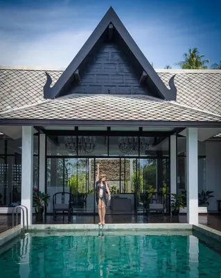 a woman is standing next to a swimming pool at Yao Bada Badoo Boutique Resort in Ko Yao Yai