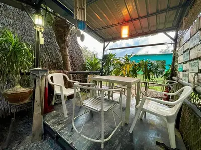 a table and chairs on a patio with plants at PhuketAirportCamping in Mai Khao Beach
