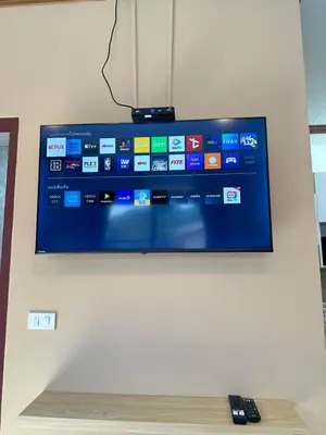 a flat screen tv on a wall with a remote control at Kata Noi Place in Kata Beach
