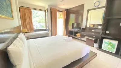 a bedroom with a white bed and a television at SM Patong Resort in Patong Beach