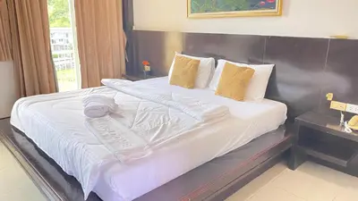a hotel room with a large bed with white sheets at SM Patong Resort in Patong Beach