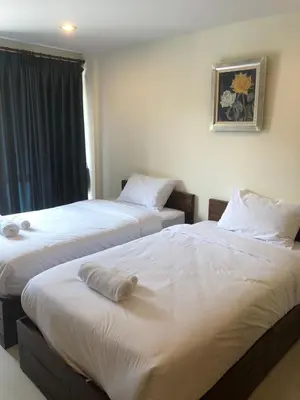 two beds in a hotel room with white sheets at Rawai Sea Beach in Phuket Town
