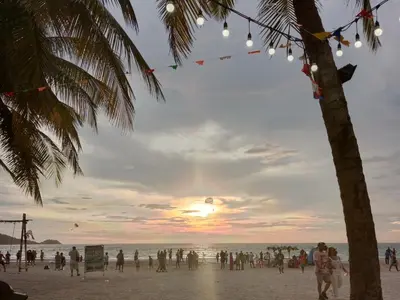 a group of people on the beach at sunset at STPhostel in Patong Beach