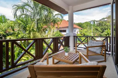 a porch with two chairs and a table on a balcony at Villa Amaya, 2 Story Tropical Oasis with Green Hills View & Pool, Kamala Beach in Kamala Beach