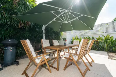 a wooden table with chairs and a green umbrella at Villa Amaya, 2 Story Tropical Oasis with Green Hills View & Pool, Kamala Beach in Kamala Beach