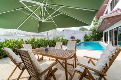 a patio with a wooden table and chairs and an umbrella at Villa Amaya, 2 Story Tropical Oasis with Green Hills View & Pool, Kamala Beach in Kamala Beach