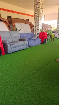 a room with green carpet and a couch and a tent at Batikseafood Airport & Room in Nai Yang Beach