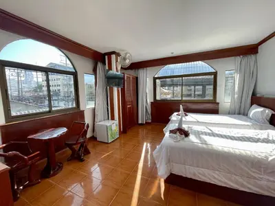 a bedroom with a bed and a desk and two windows at Centre Point Patong in Patong Beach
