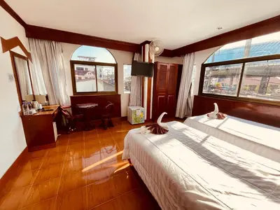 a hotel room with two beds and a desk and window at Centre Point Patong in Patong Beach
