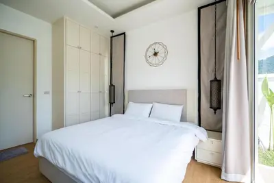 a bedroom with a white bed and a clock on the wall at Deluxe pool villa at Kamala Garden View in Kamala Beach